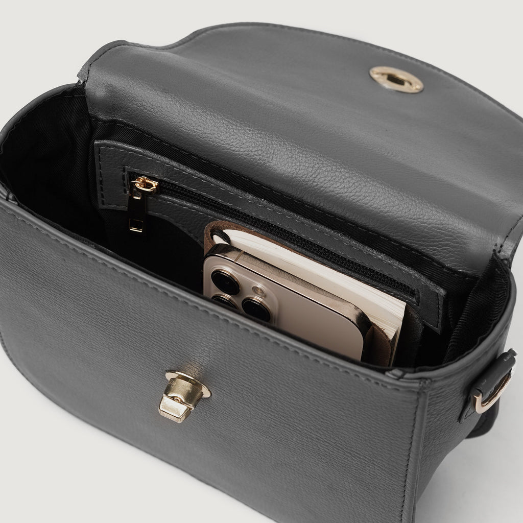 Inside view of The Sandra Grey Leather Saddle Bag showcasing smartphone and organized compartments.